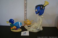 Lenox figurine with Nemo and Dory characters on coral base, approximately 8 inches tall shown with ruler, alongside a smaller collectible figurine with blue background.