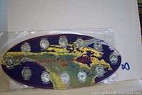 Full set of 12 Canadian Millennium quarters from 2000 displayed on blue chipboard shaped like a stylized map with gold and red lettering.