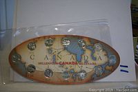 Oval chipboard housing 12 dated 1999 Canadian quarters depicting provincial/territorial designs with map background for Millennium Canada.