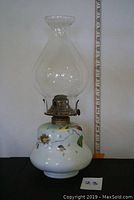 Oil lamp from front with ruler showing height approx. 15 inches, hand-painted floral white glass base, clear fluted glass chimney.