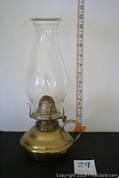 Front view of antique brass oil lamp with clear glass beaded hurricane chimney, with measuring tape showing height of approx 12.5 inches