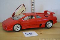 Side profile of 1:18 scale red Lamborghini Diablo diecast with left scissor door open, showing door design and car profile.