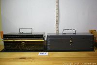 Two metal lock boxes side by side, showing size and external details with handles and key slots.