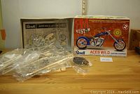 Complete view of the Revell Aces Wild custom chopper model kit box with plastic parts, tires, and decals laid out on table