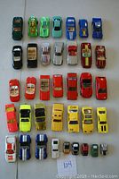 Top-down and various angled views of 37 Hot Wheels diecast cars arranged in rows by color and model type on a white surface.