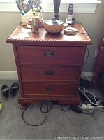 Front view of nightstand showing the three drawers with metal handles, scratches, and dings on wood.