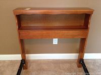 Front view of the wooden twin bed headboard showing the curved top, shelf, and wood finish with scratches.