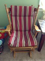 Front view of wooden glider chair with striped cushion showing cushion stains and wood wear.