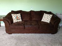 Front view of brown Ashley couch with three seat cushions and two throw pillows, showing signs of wear and stains on cushions.