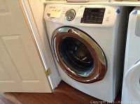 Left-front angle view of white Samsung front-load washer installed between cabinetry.