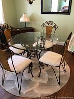 Full view of round glass top table with four matching chairs arranged around it, showing overall design and condition.