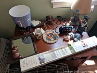 Overview of bathroom decor collection including lamp, clock, mirror, trash bin, and mini blinds on wooden table