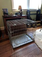 Metal wire collapsible pet crate showing wire door and plastic tray base