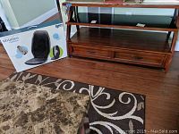Wood TV stand with two drawers and glass shelf with shiatsu chair massager box beside it.