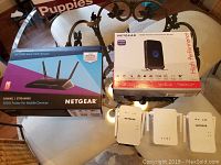 Two boxed Netgear routers and three white Netgear WiFi extenders on a table
