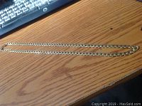 Full length photo of the gold tone chain laid on a wooden surface, showing the overall appearance and size.