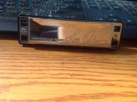 Front view of Lee Oskar EV 10 Tremolo harmonica showing metal cover plate with engraved Lee Oskar logo and model name.