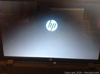HP laptop screen displaying the startup HP logo, laptop powered on and keyboard visible.
