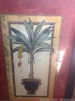 Full view of large framed painting depicting a potted tropical palm or banana tree with yellow fruit and red flower against a light background.