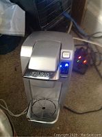 Top-down view showing the Keurig logo on chrome lid and LED lights on control panel