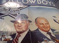 Close-up image of vintage 1984 Dallas Cowboys silver anniversary poster featuring artwork of two men in suits and Cowboys branding.