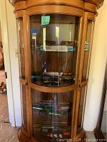 Three-shelf curved glass display cabinet showing the full assortment of HO scale model trains.