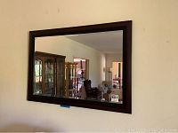 Front view of beveled wall mirror mounted on wall, showing reflections and condition.