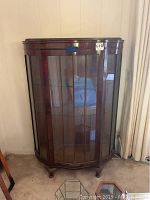 Front view of the vintage wood display cabinet with glass door and curved glass sides.