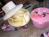 Photo shows two vintage hats and two hat boxes arranged on a surface.