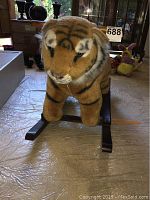 Front view of the plush tiger rocker showing the tiger's face and wooden rocker base.