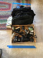 Wide view of all items including cameras, lenses, cases, and Sony Watchman box on floor