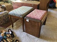 Two vintage benches, one with floral upholstery and curved wooden legs, the other with pink patterned upholstery and wooden frame, placed on a floor near dolls and furniture.