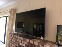 Samsung TV monitor resting on a brick ledge with a black stand in place, screen facing forward.