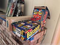 Photo of a sealed 1988 Fleer Baseball trading cards box and a 1988 Donruss Baseball Puzzle and Cards box on a ledge.