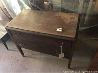 Front angled view of the vintage wooden 2-drawer dresser showing overall wear and laminate damage on top.