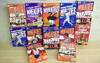 Photo of ten empty Wheaties cereal boxes and one Frosted Mini-Wheats cereal box, each featuring different athletes or sports themes. Boxes arranged in two rows on a plain surface, well-lit to show front designs.
