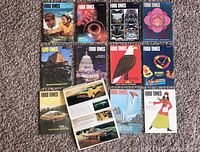 Top-down photo of 12 Ford Times magazines laid out in a 4x3 grid showing various colorful covers including people, a musical instrument, stylized faces, a flower, a building, the US Capitol, an eagle illustration, a steering wheel, vintage cars, a sailboat, and a woman in 1970s fashion.