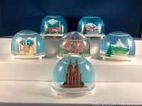 Photo showing all six snow globes arranged in two rows, displaying the variety of European landmarks inside.