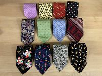 Lot of 12 assorted men's neckties displayed side by side in two rows showing various dress and novelty patterns.