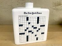 Front side of cookie jar showing New York Times crossword puzzle grid titled 'Food For Thought'.