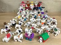 Full lot of 56 Disney 101 Dalmatians McDonalds plastic figures displayed on a table, showing a wide variety of Dalmatian characters and accessories.