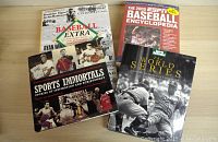 Four baseball books including Sports Immortals, Baseball Extra, ESPN Baseball Encyclopedia, and Sports Illustrated The World Series arranged on a table.