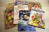 Seven vintage art instruction books displayed together, showing detailed cover art related to flowers, still life, pastels, and seascapes.