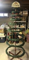 Full front view of the Jim Shore store display ornament tree showing its metal frame, green garland on circular tiers, and overall height and width.