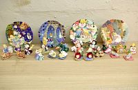 Four storybook miniature tea sets displayed together including plates and figurines.