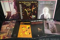 Group photo showing seven vinyl jazz albums including The Smithsonian Collection of Classic Jazz, Dave Brubeck Greatest Hits, Getz/Gilberto, Milt Hinton & Marty Grosz, The Best of Pete Fountain, George Shearing Blues Alley Jazz, and another with a close-up of a musician with a saxophone.