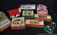 Multiple Plasticville and Bachmann kits in original boxes alongside a few assembled buildings and plastic fences.