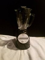 Front view of black Oster blender with glass pitcher and 14 speed buttons.