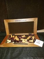 Wooden chess board with sliding lid open showing scattered chess pieces inside.