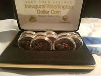 Ten 24KT gold layered commemorative coins with Barack Obama image in a black display case.